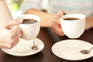 Two women with cups of coffee close up