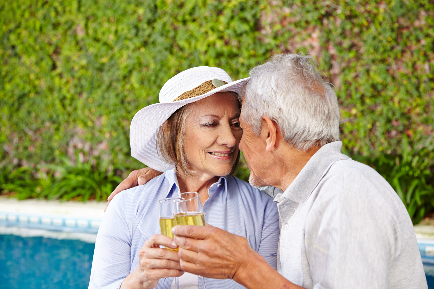 Zwei Senioren mit Sekt am Pool