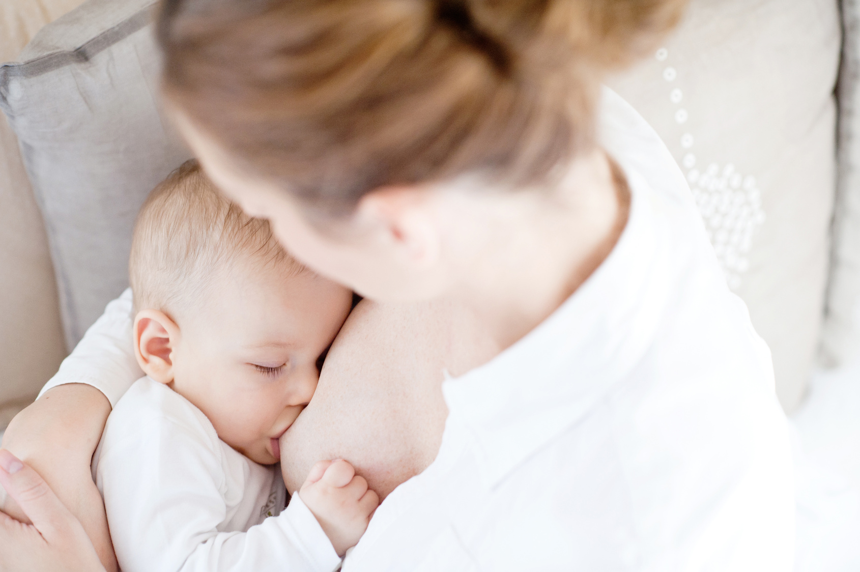 Young mother breastfeeding the newborm baby – indoors