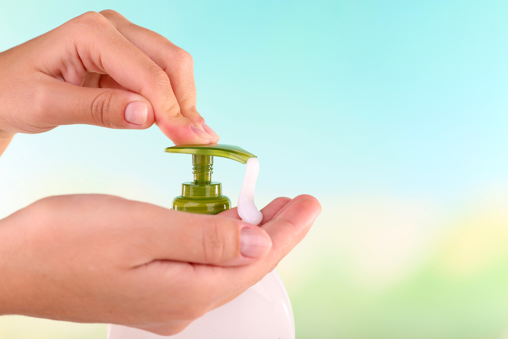 Female hands using liquid soap on light background