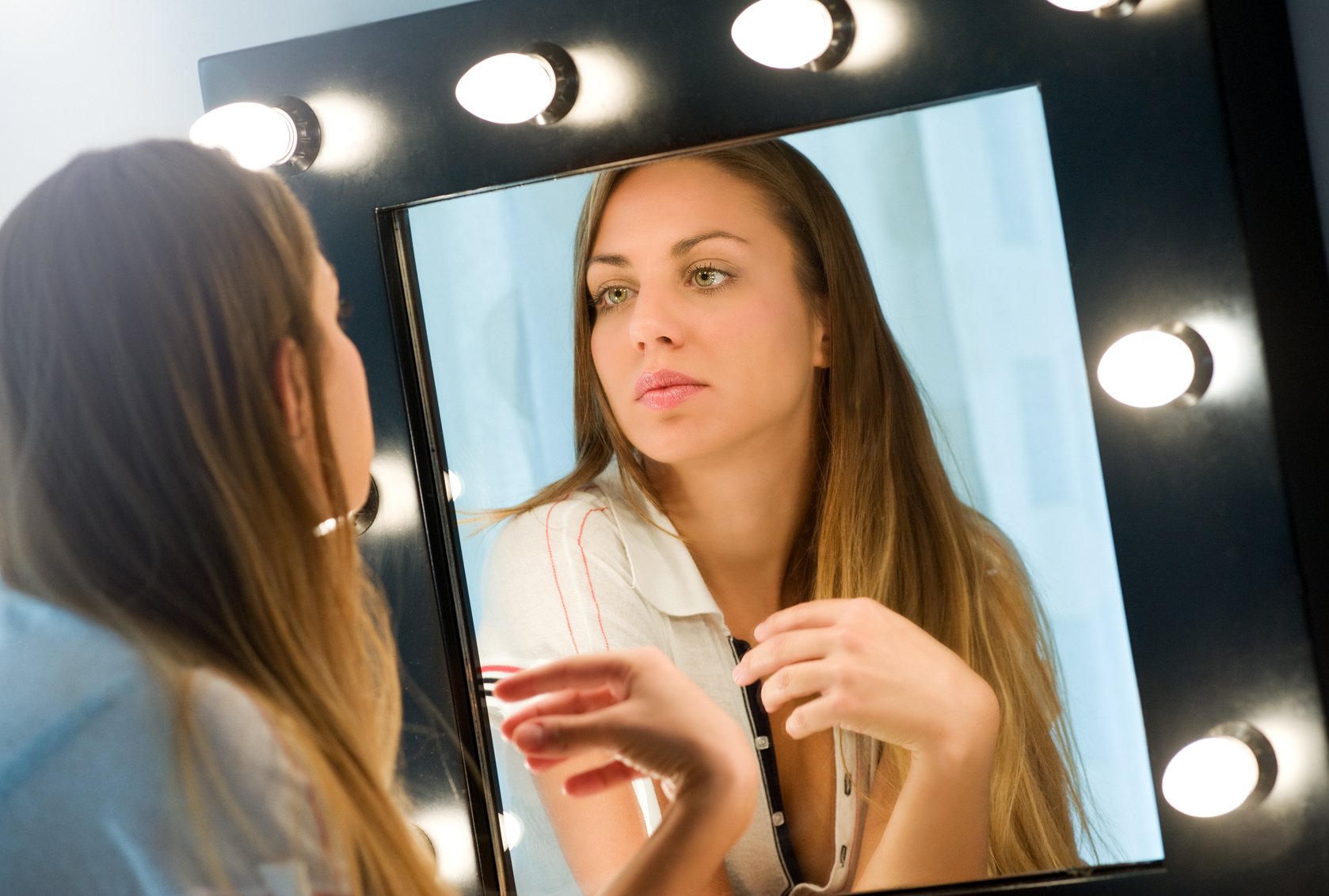 Young woman admiring herself in the mirror