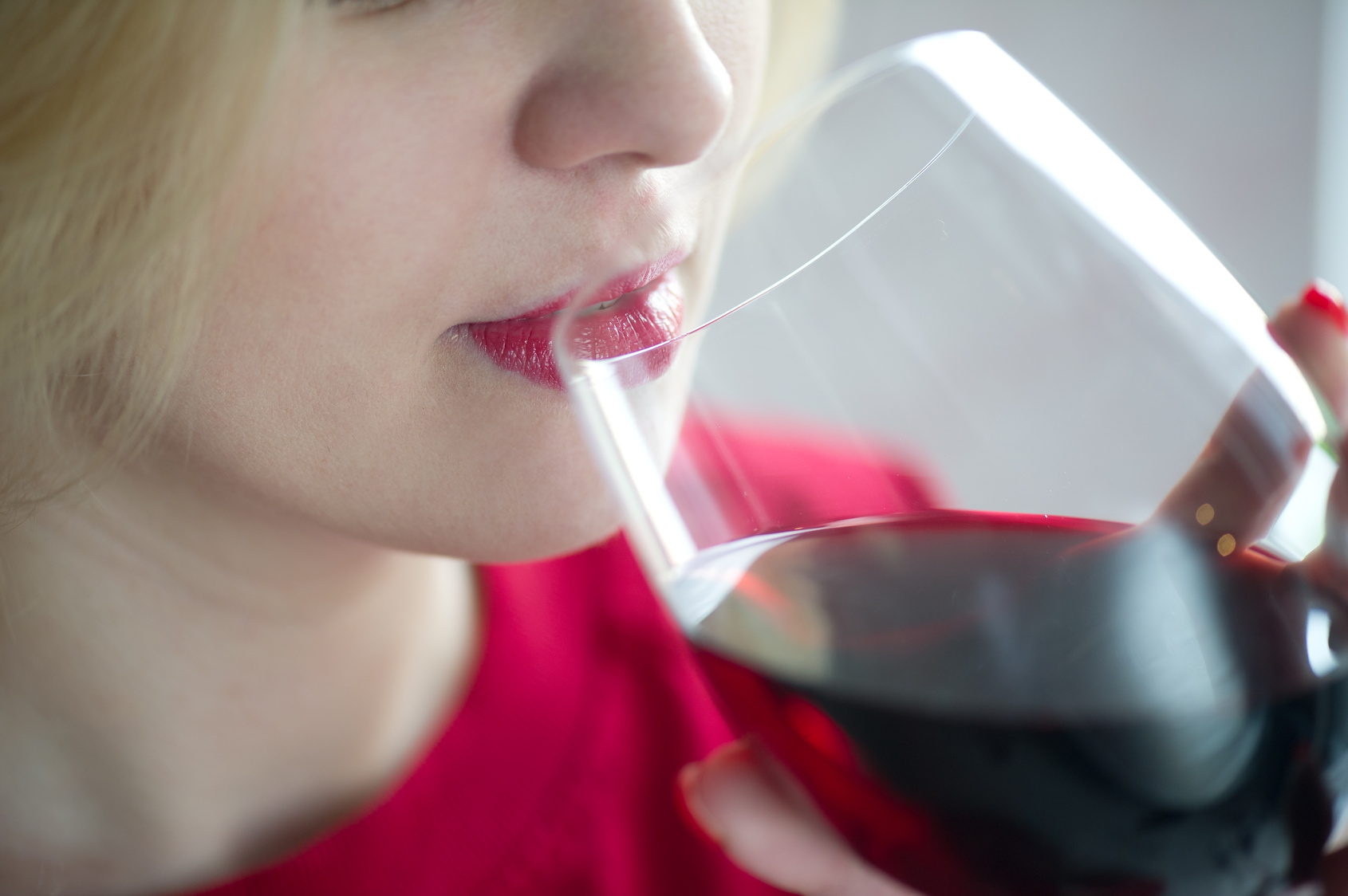 Woman drinking red wine with red lips – close portrait