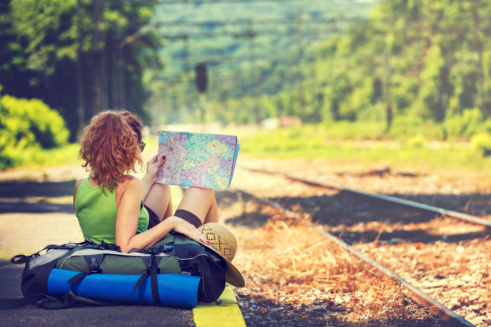 Girl wearing backpack holding map, waiting for a train.