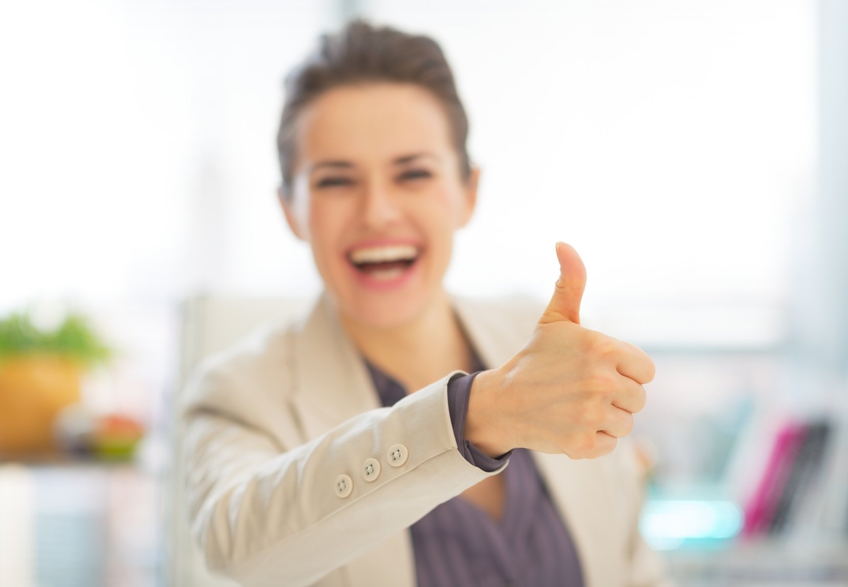 Closeup on smiling business woman showing thumbs up