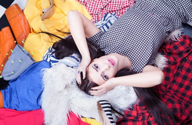 Stressed young woman lying down on a pile of clothes