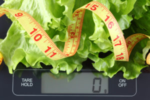 Green lettuce and tape measure on kitchen scale