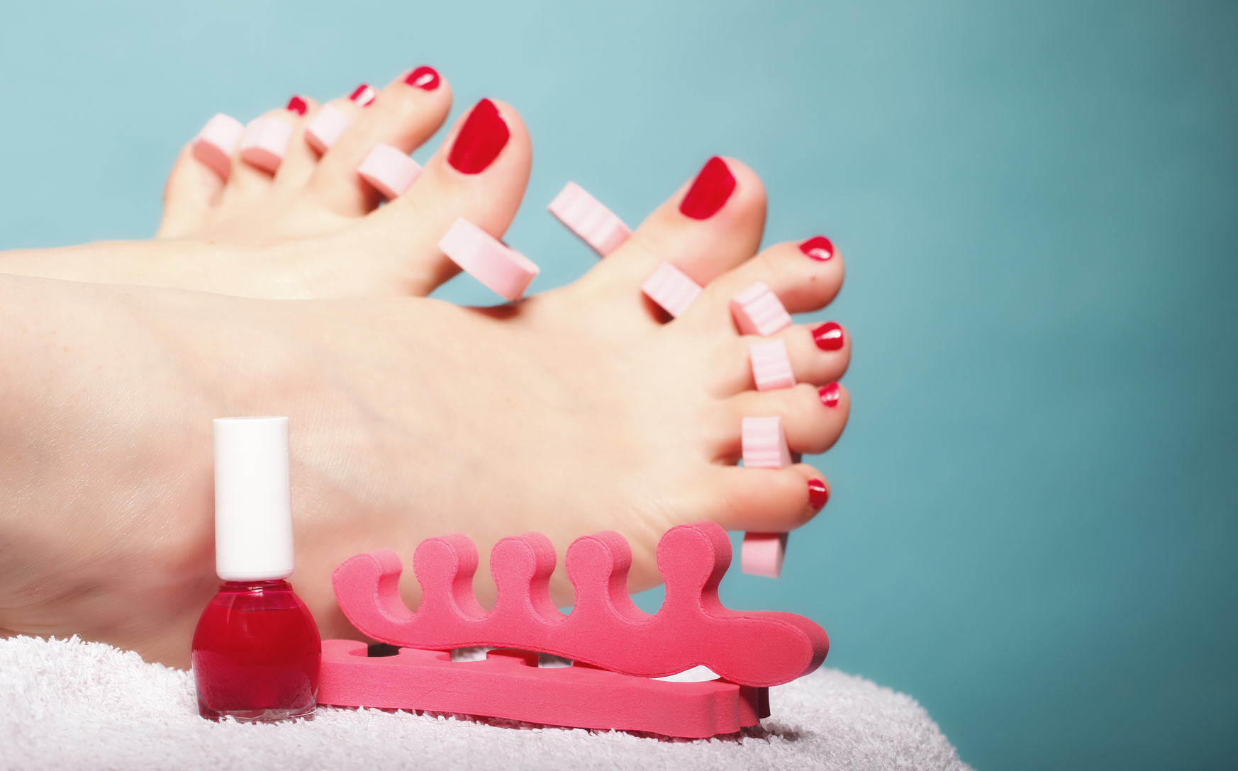 foot pedicure applying red toenails on blue