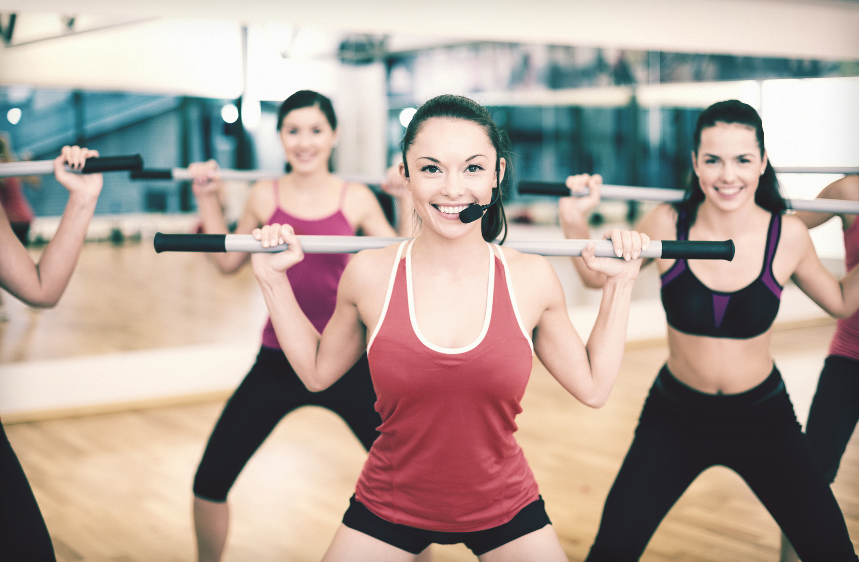 group of smiling people working out with barbells