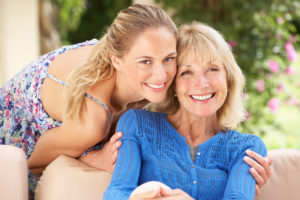 Senior Woman With Adult Daughter Relaxing On Sofa At Home