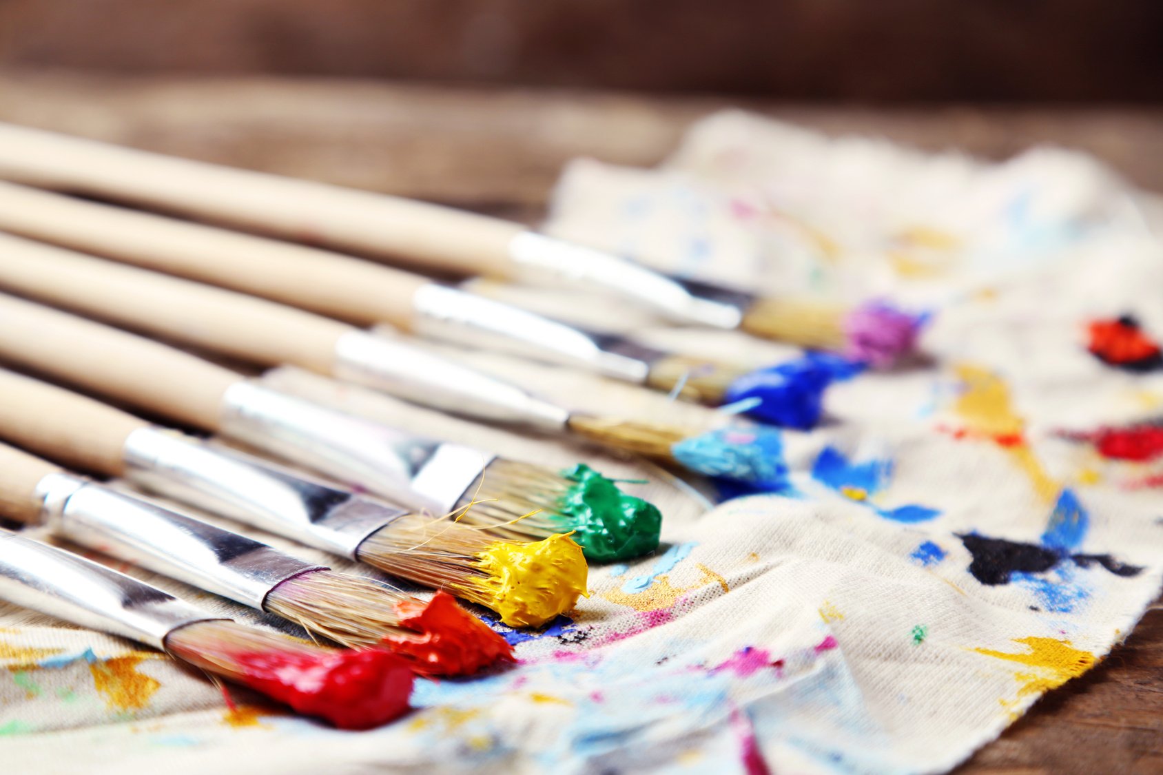 Brushes with colorful paints on dirty cloth