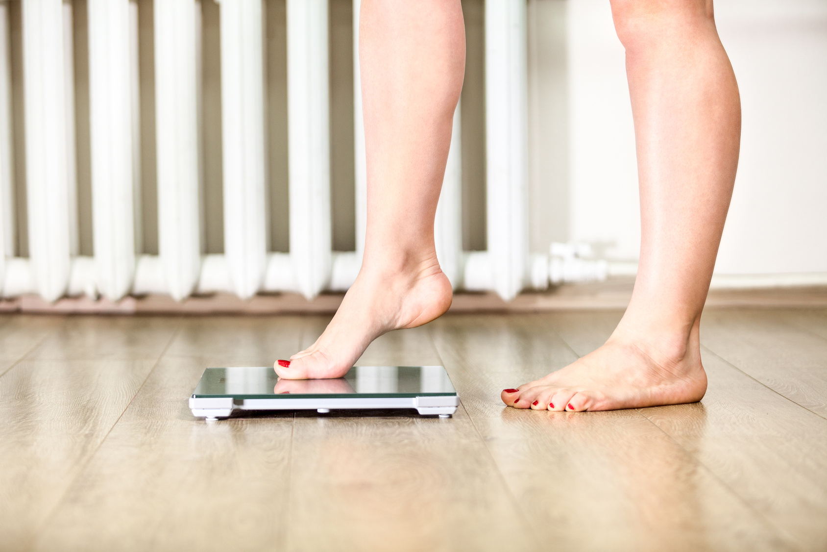 Caucasian female legs gently tread on the floor scales