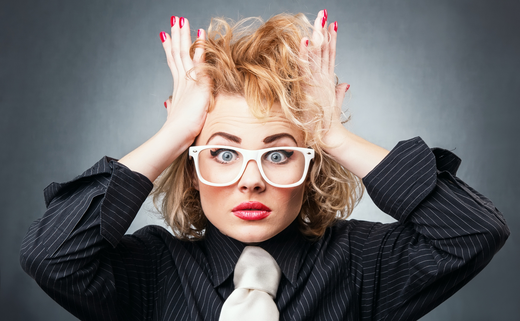 Shocked young business woman in a panic, isolated on gray