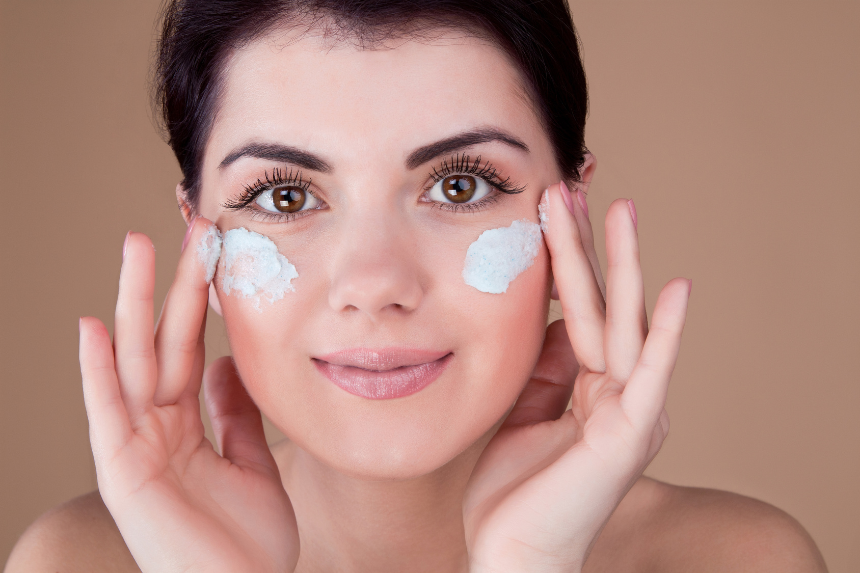 girl with cream on her cheeks with both hands near the face