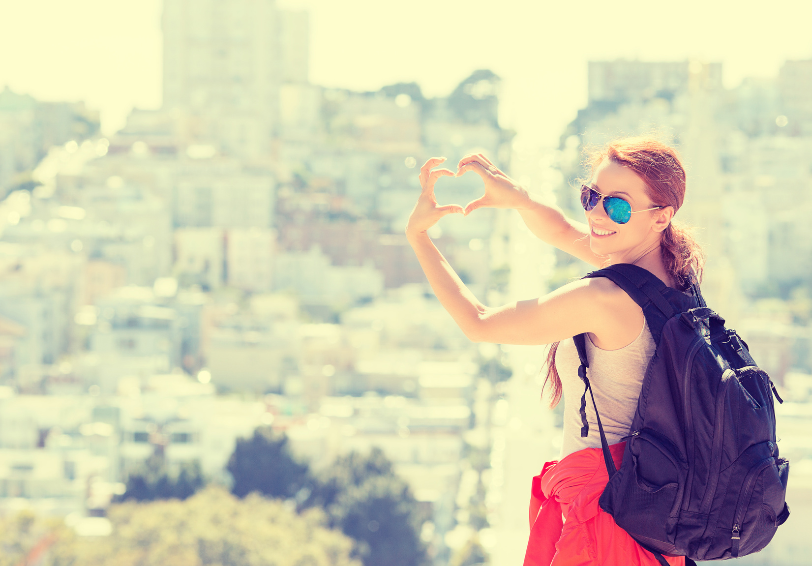 Young woman in San Francisco smiling making hand shaped heart