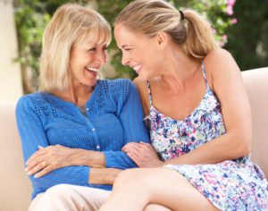 Senior Woman With Adult Daughter Relaxing On Sofa At Home