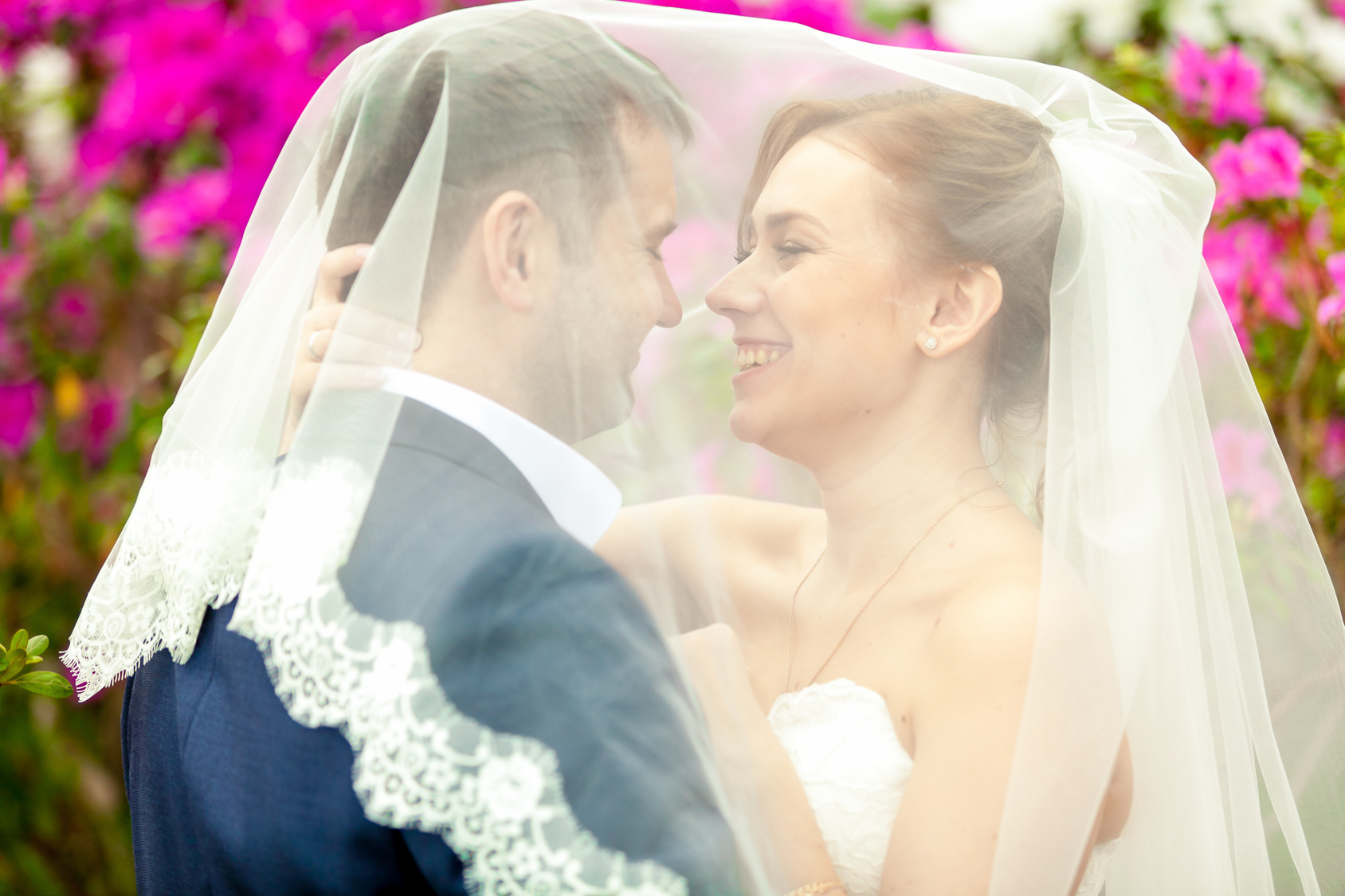 Closeup portrait of just married couple under white veil