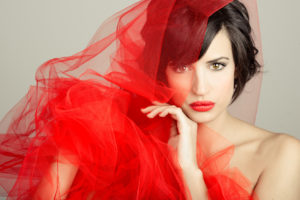 Beautiful girl with a red tulle. Studio photograph