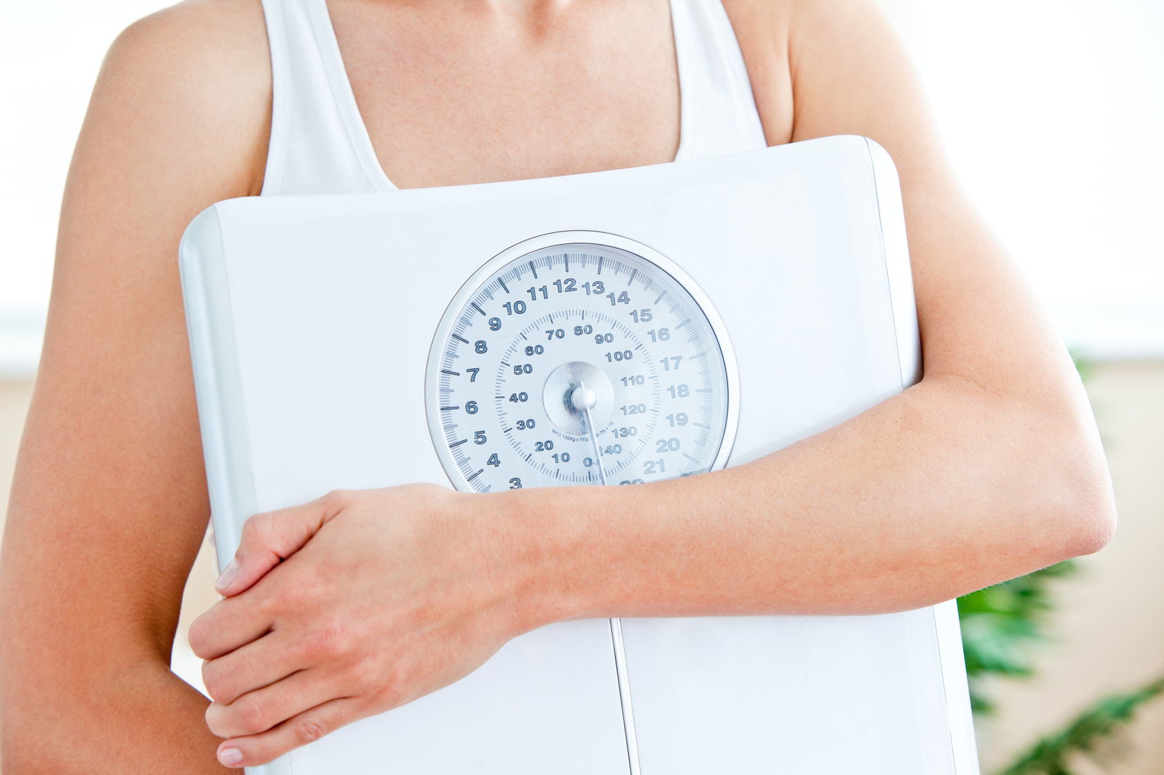 Close-up of a hispanic woman holding a scale in her living-room