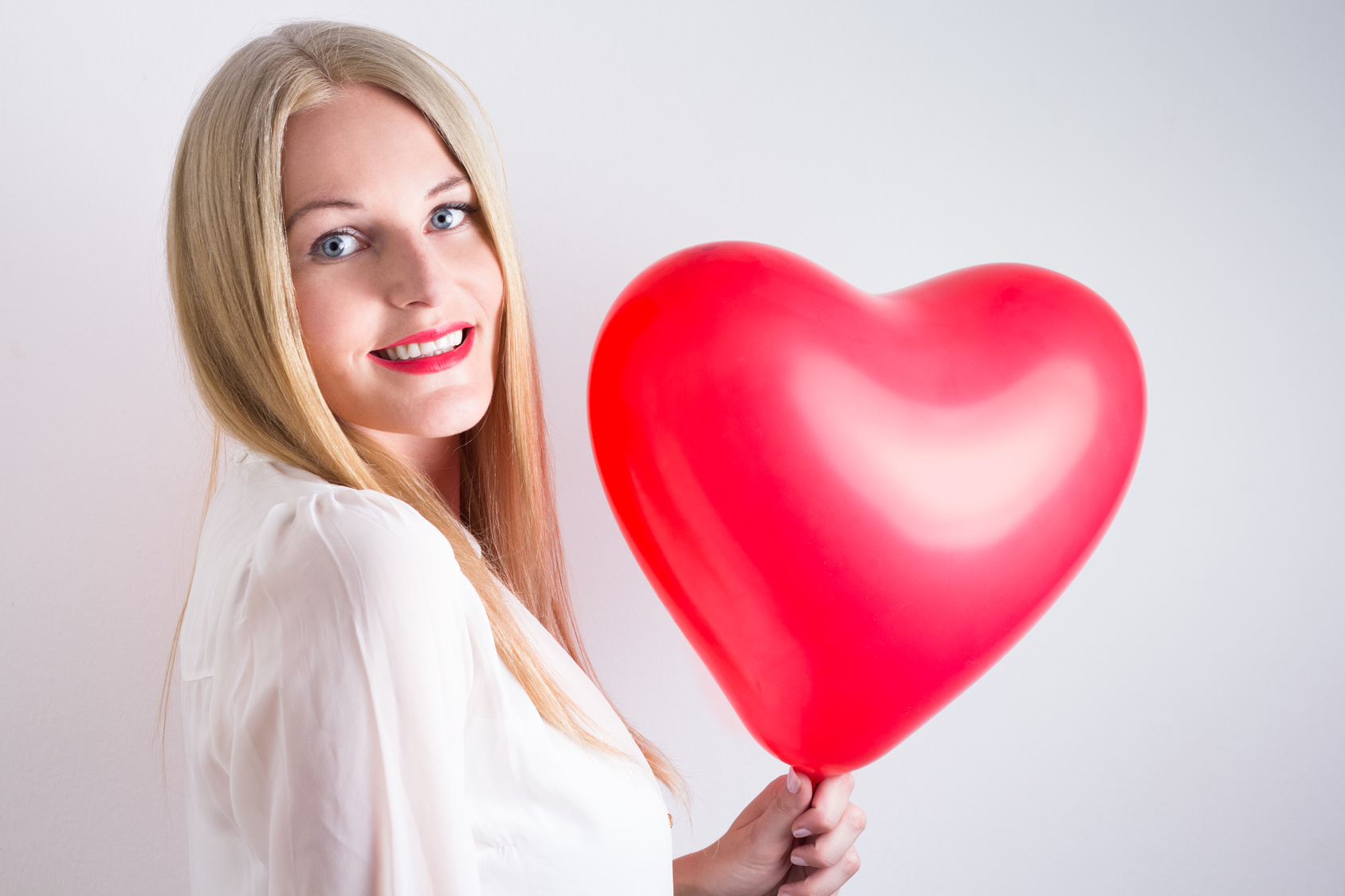 Woman holding a red heart balloon