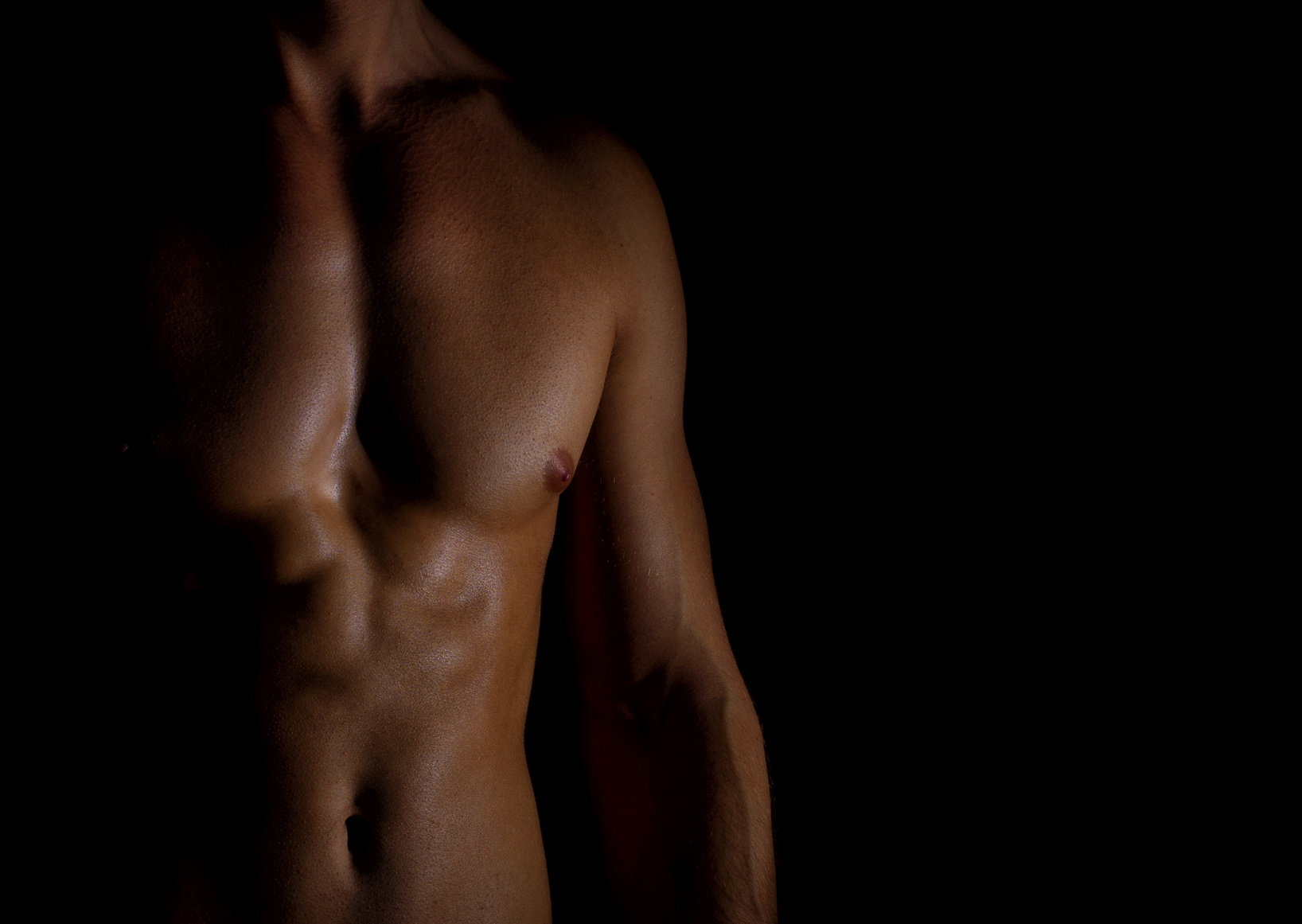 Unrecognizable muscular male body on black background.