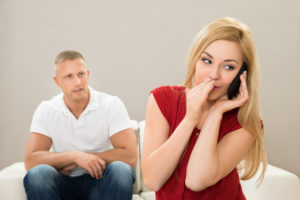 Wife Talking On Mobile Phone While Husband On Sofa