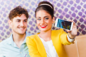 Woman and man sitting at cafe, taking a selfie
