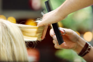 Hairdresser trimming blond hair with scissors