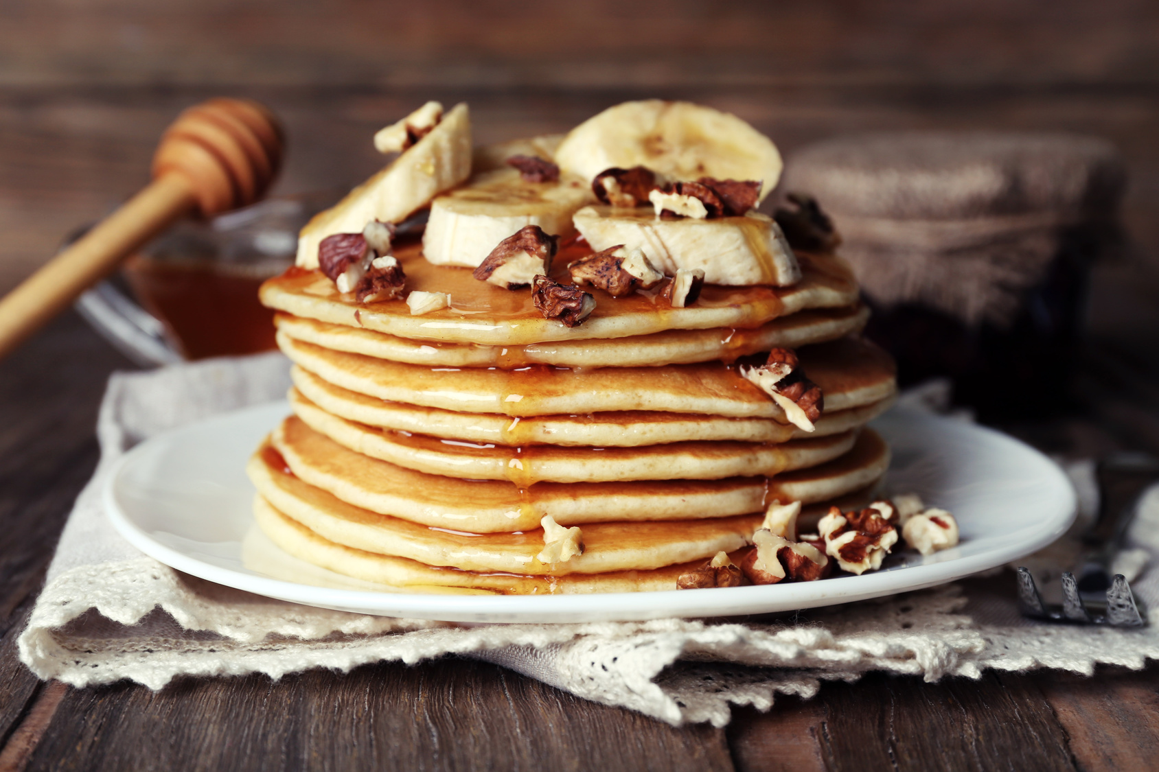 Stack of delicious pancakes with chocolate, honey, nuts and