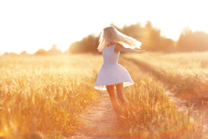 happy girl on the road in a wheat field at sunset