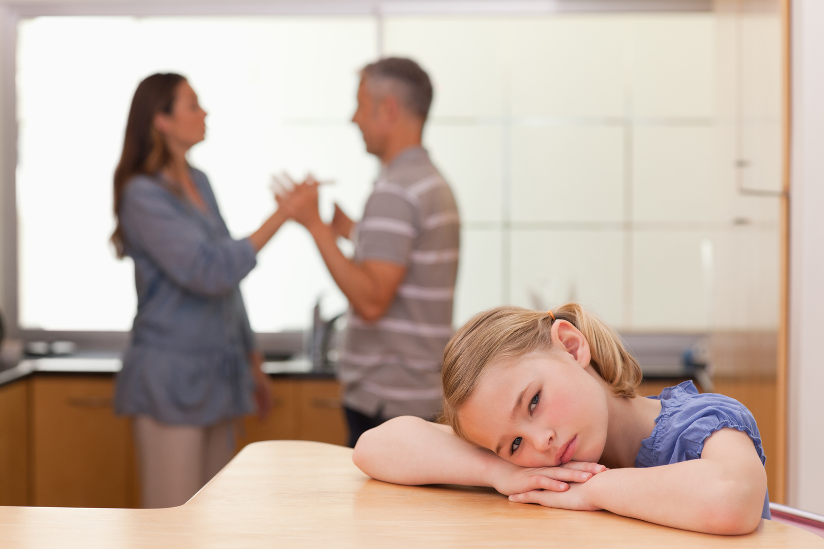 Sad girl hearing her parents arguing in a kitchen fight