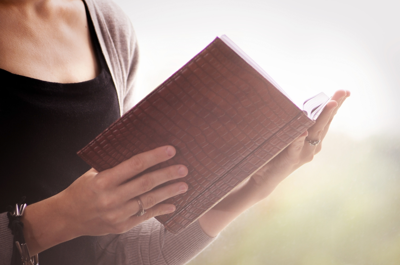 background girl sitting at the window, holding an open notebook,