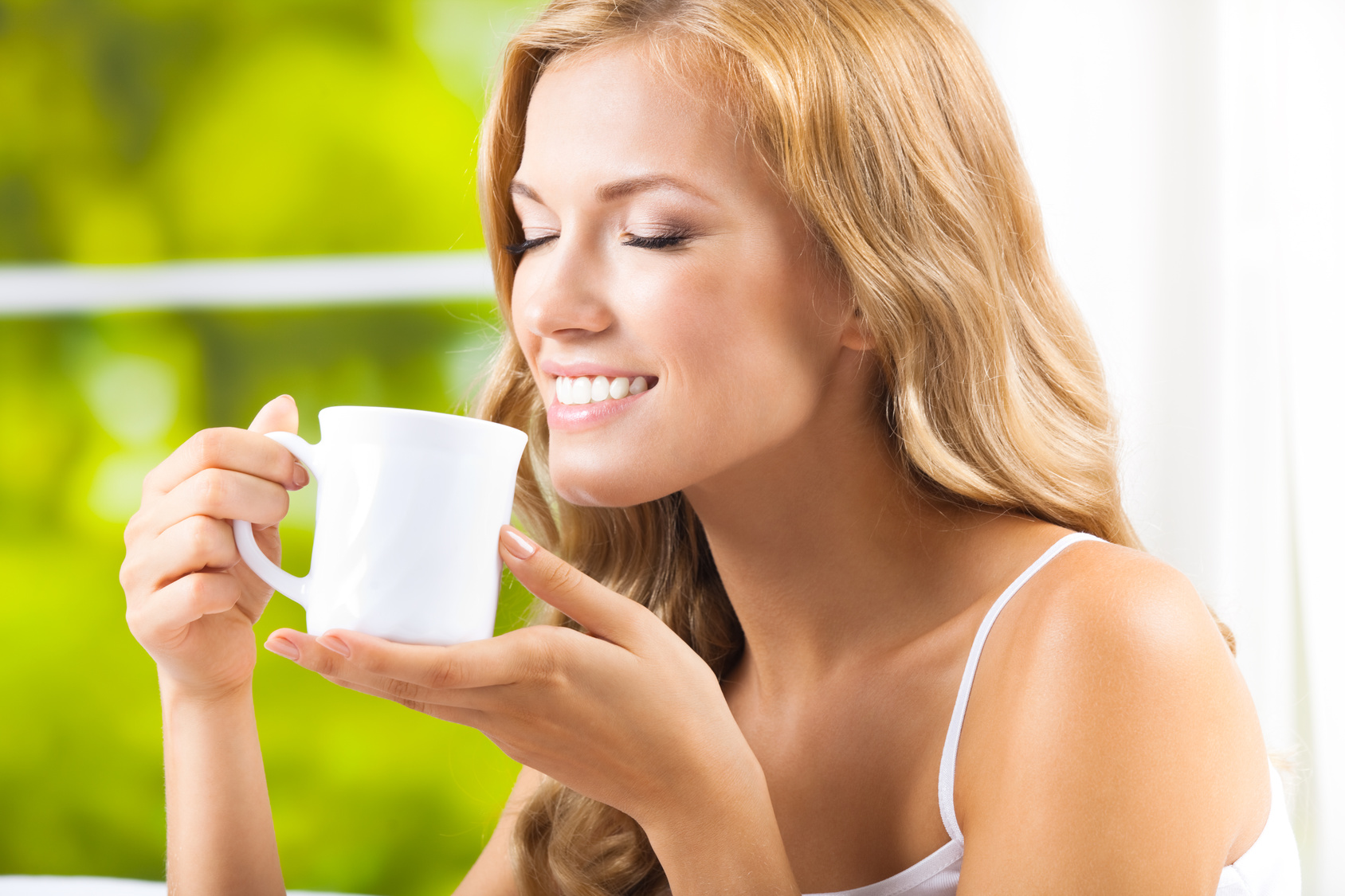 Young woman drinking coffee or tea, at home