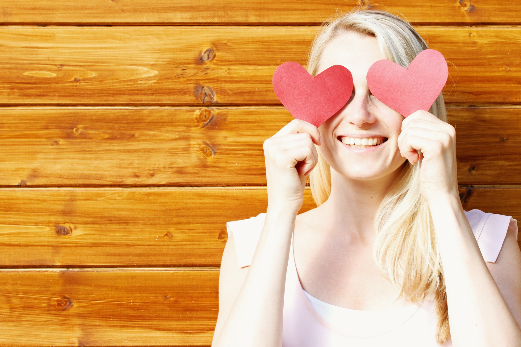 young beautiful smiling woman with paper hearts over eyes – fall