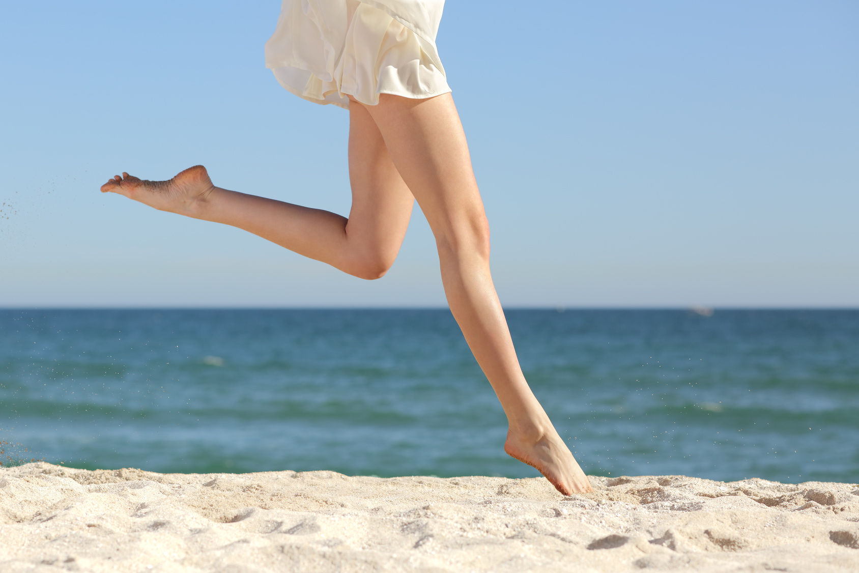 Beautiful woman long legs jumping on the beach