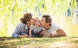 Happy parents kissing toddler boy