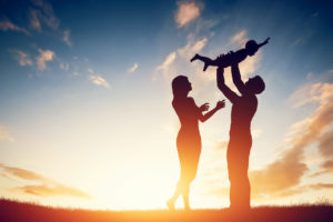 Happy family together, parents with their little child at sunset.