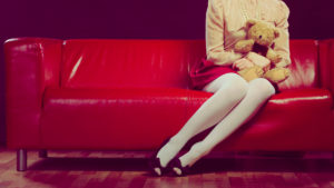 childlike woman and teddy bear sitting on couch