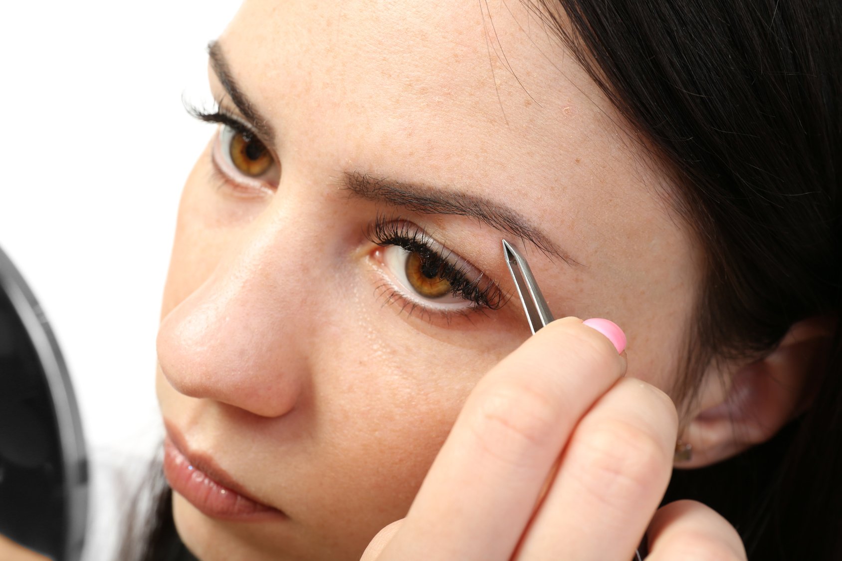 Young woman plucking eyebrows with tweezers close up