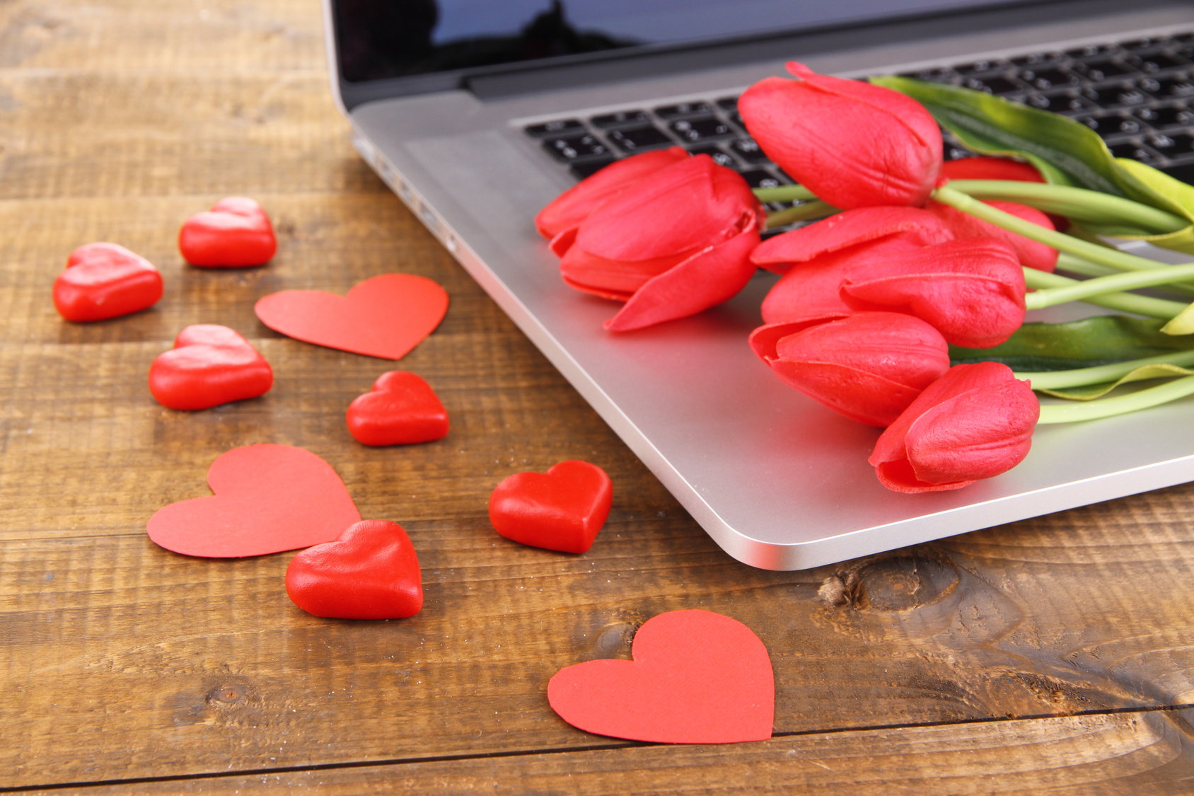 Computer with red hearts and flowers on table close up