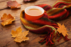 Autumn leaves, book and cup of tea on wooden table in studio