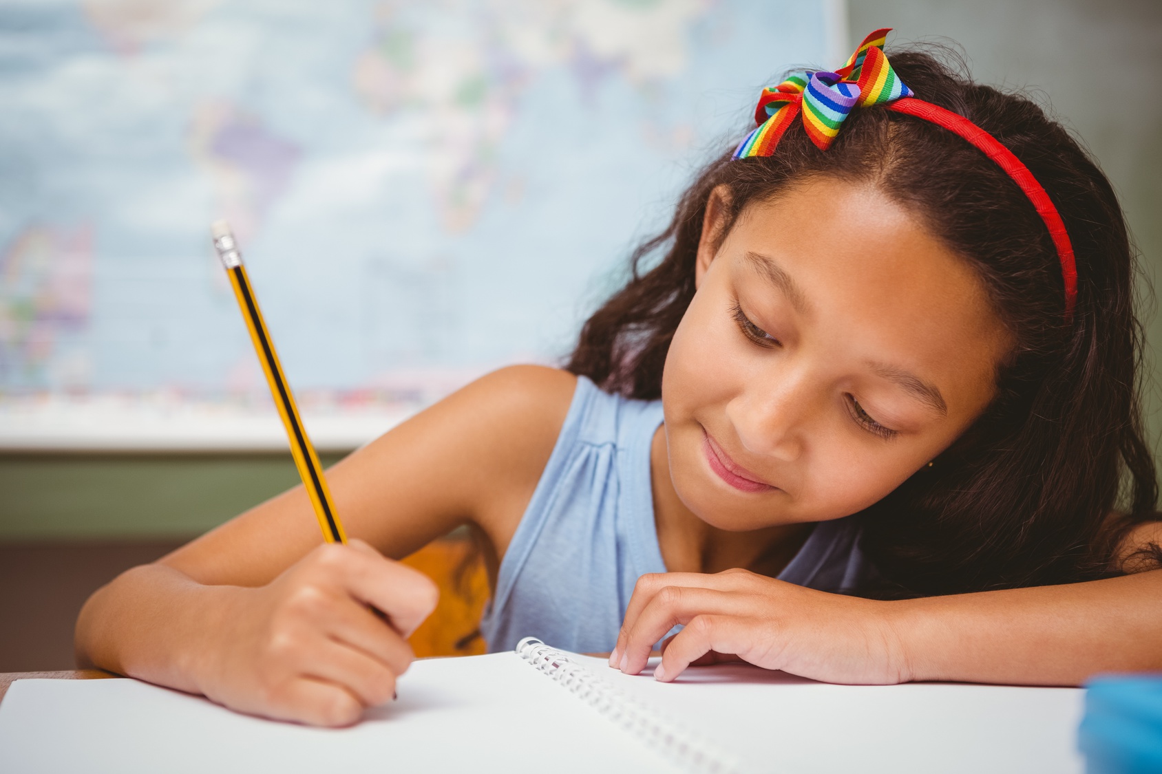 Little girl writing book in classroom