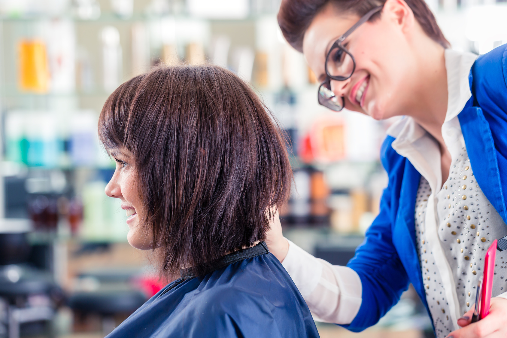 Hairdresser cutting woman hair in shop