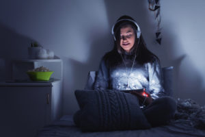Teenage girl watching movie on tablet in bed at night