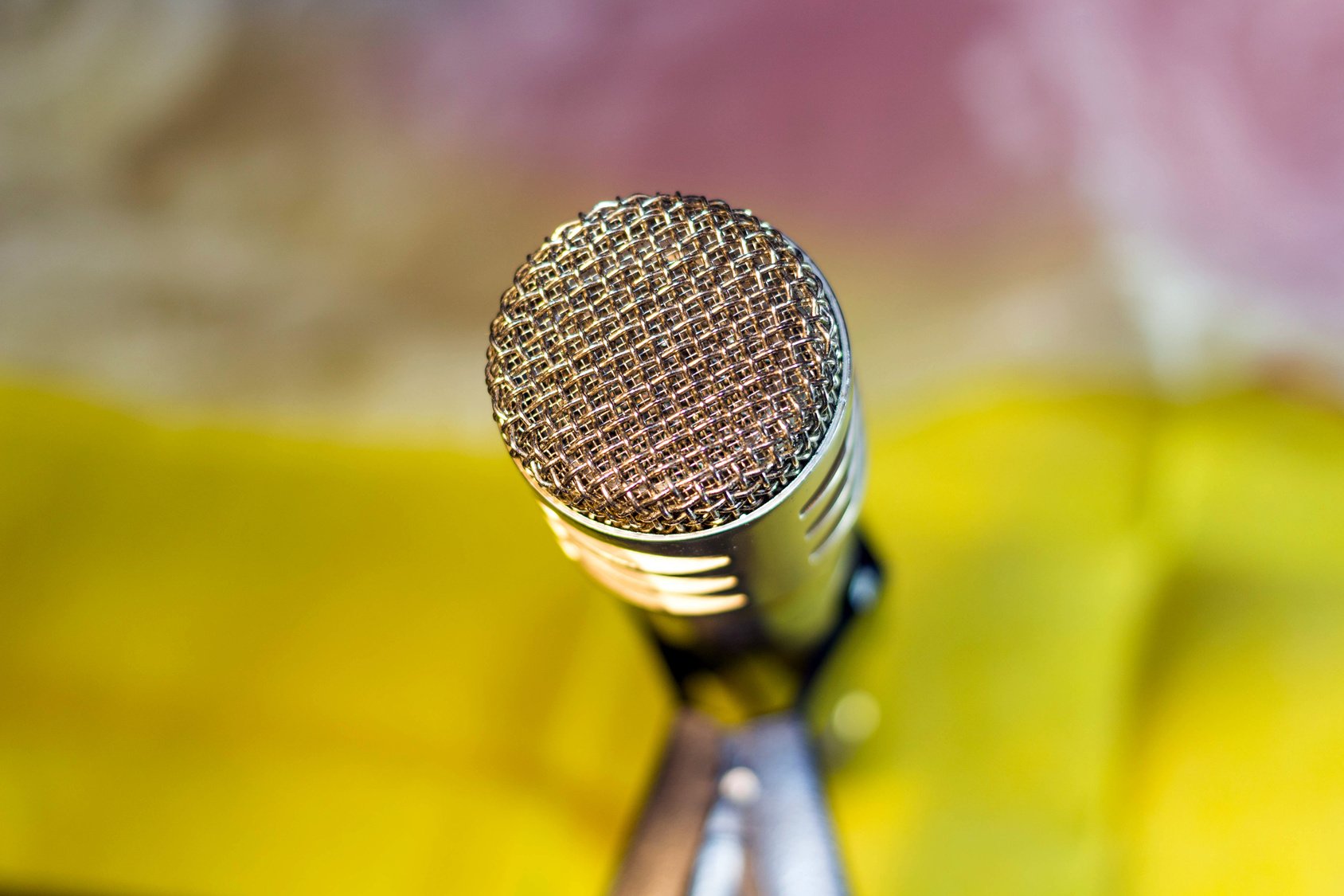 Silver microphone on blurred yellow background
