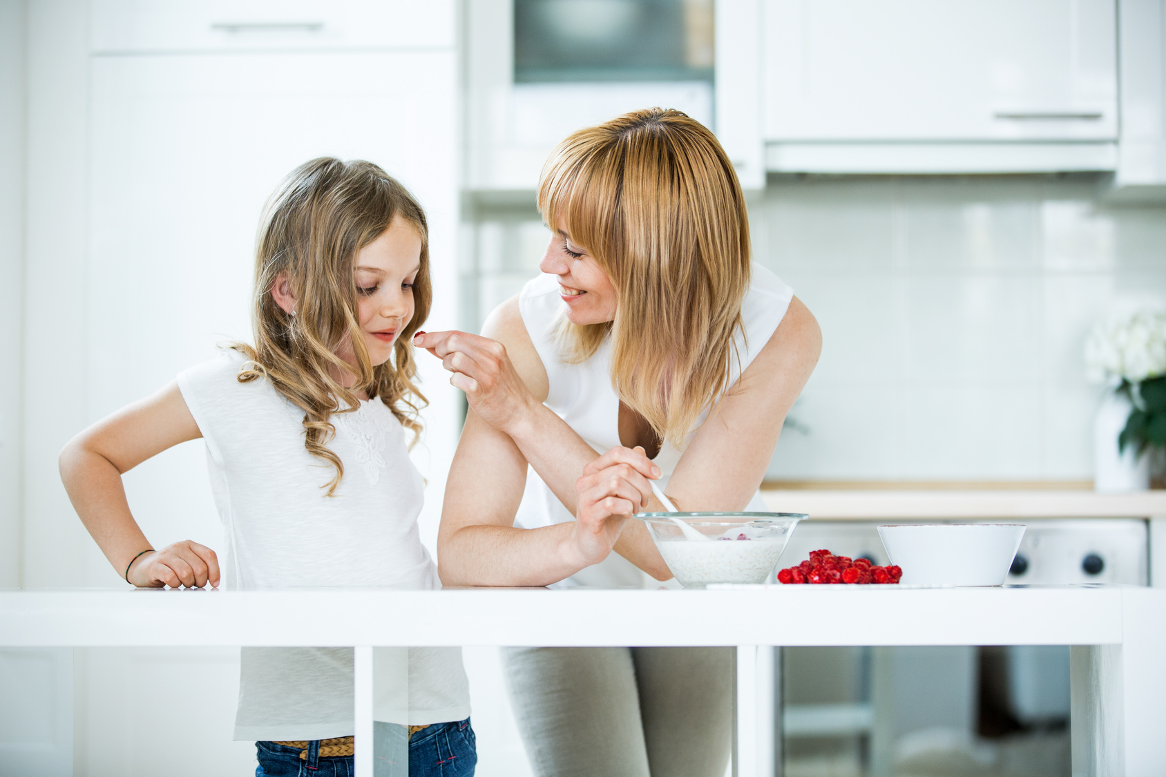 Mutter und Tochter machen Müsli mit Himbeeren