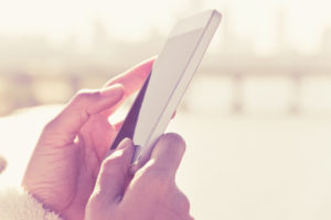 Women hand holding a smart phone with sunrise background