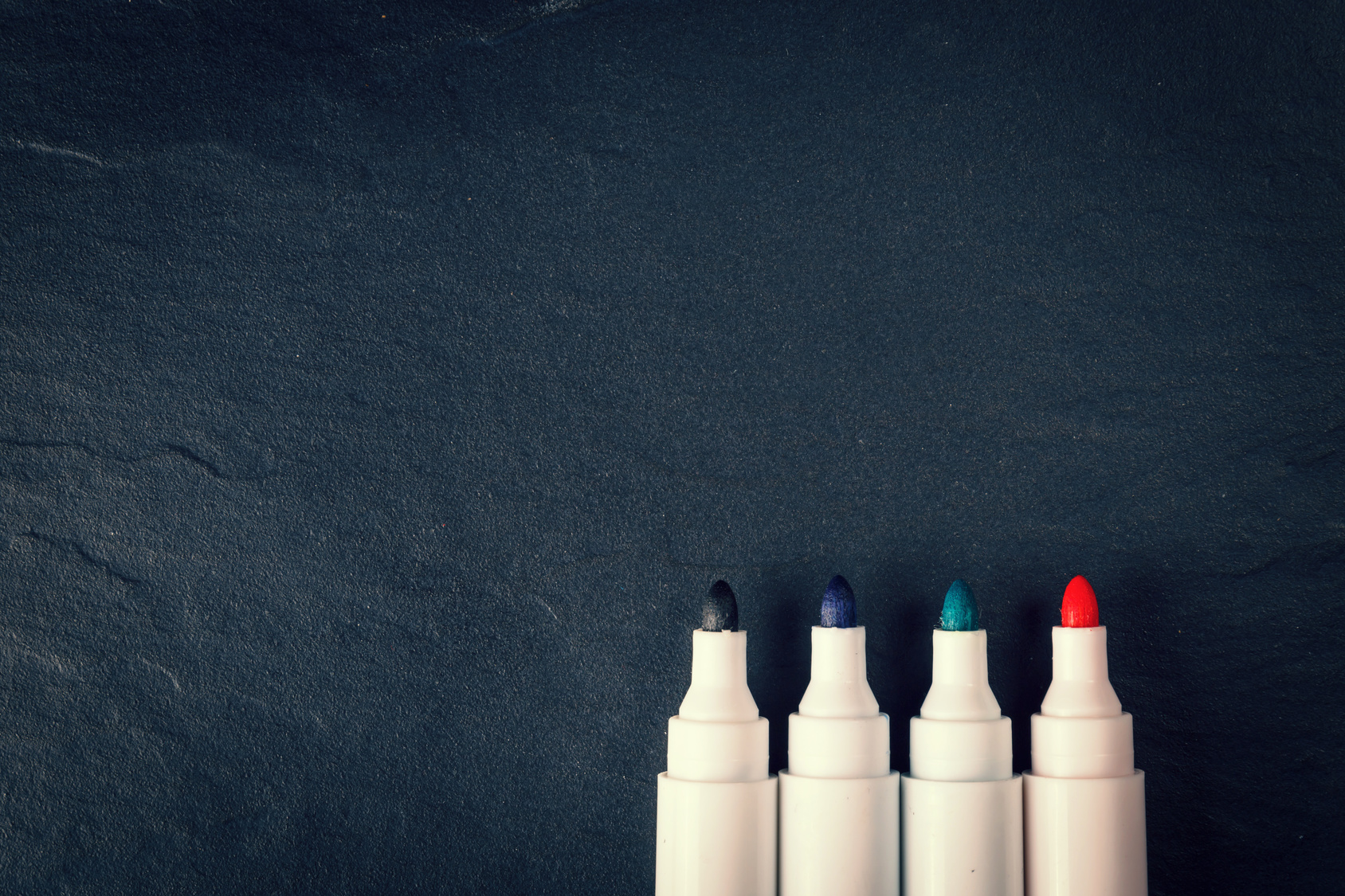 four markers on black background, vintage color tone pen