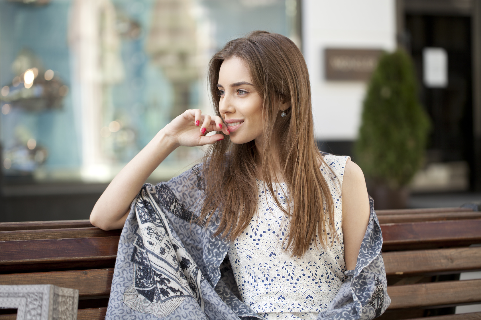 Brunette calm woman sitting on the bench in summer street