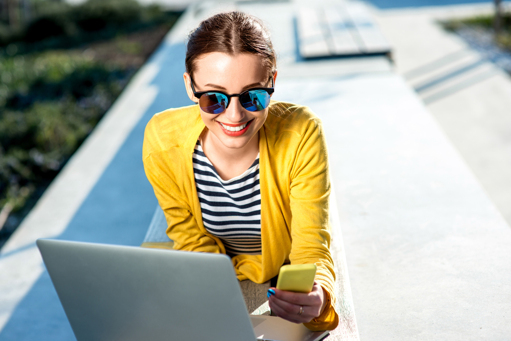 Woman with laptop and phone outdoors