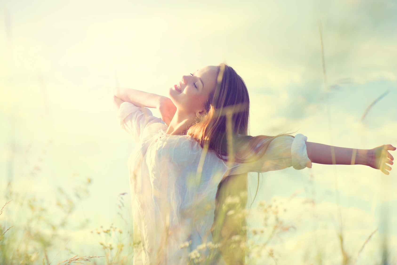 Teenage model girl in white dress having fun on summer field